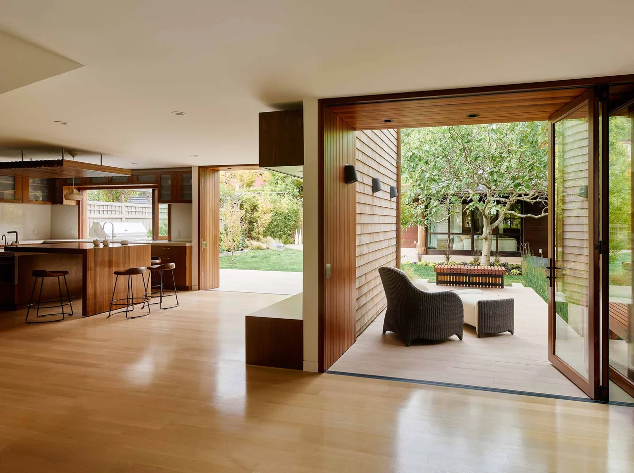 Kitchen opens through large glass doors to a covered patio and landscaped garden in the Claremont Residence.