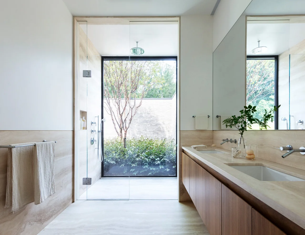 The New Canaan Pavilion bathroom features a glass shower door opening to an outdoor garden with natural light.