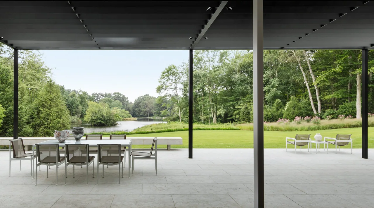 The New Canaan Pavilion features a covered patio with modern outdoor furniture and views of the surrounding landscape and river.