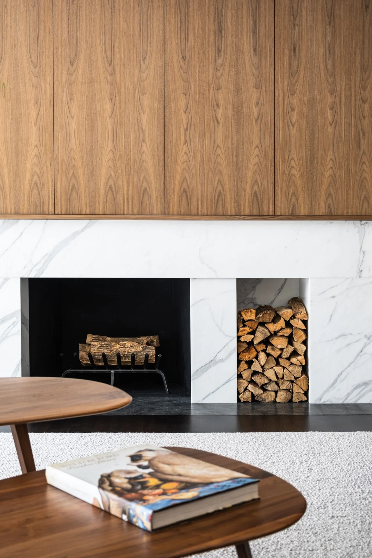 Fireplace with white marble surround and wood paneling above in modern living space.