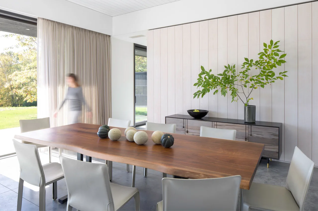 Dining room with a large wood table and white chairs in Sackett Hill House by Deborah Berke & Partners.
