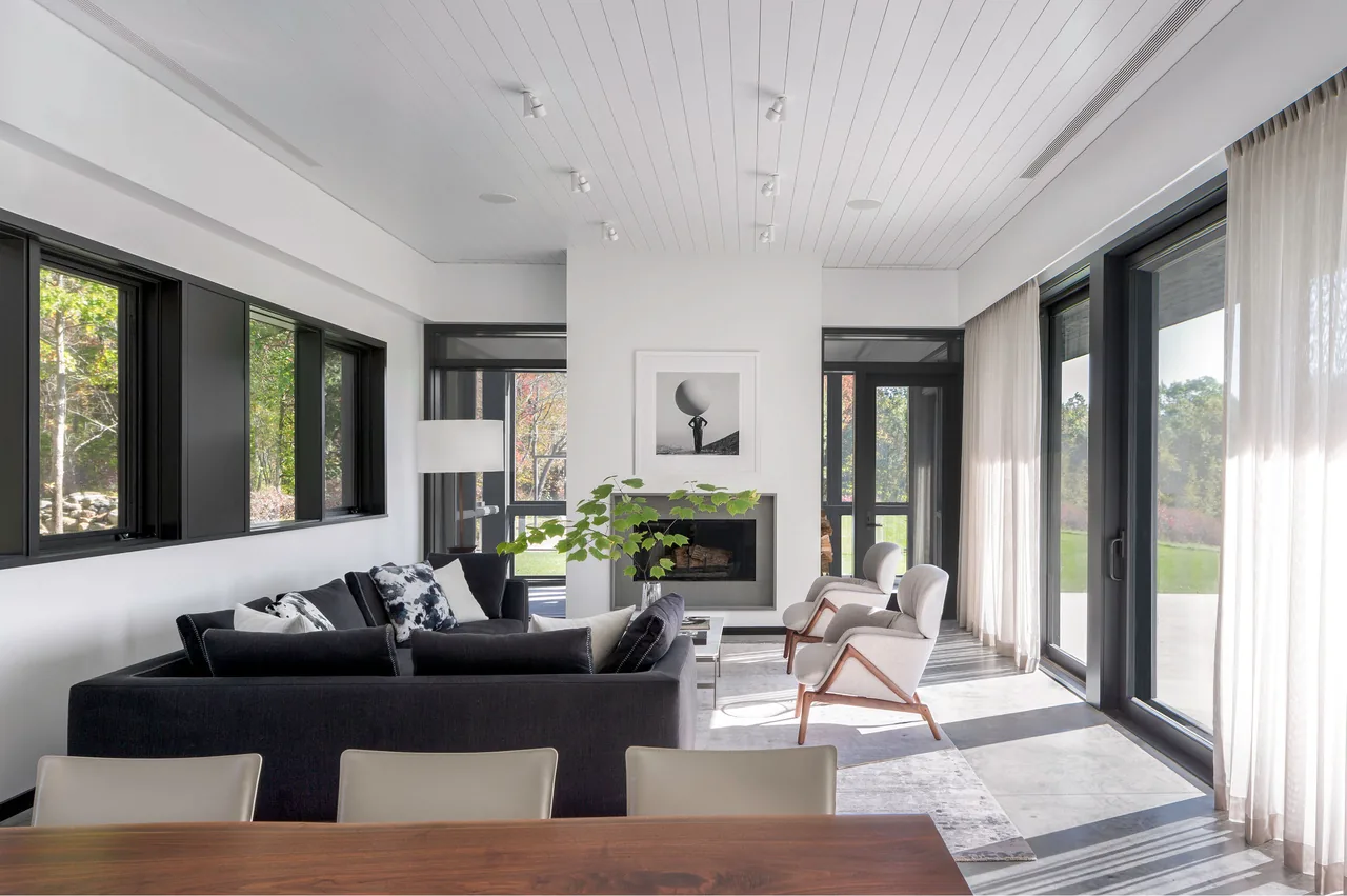 Living room in the Sackett Hill House features floor-to-ceiling sliding glass doors and a central fireplace.