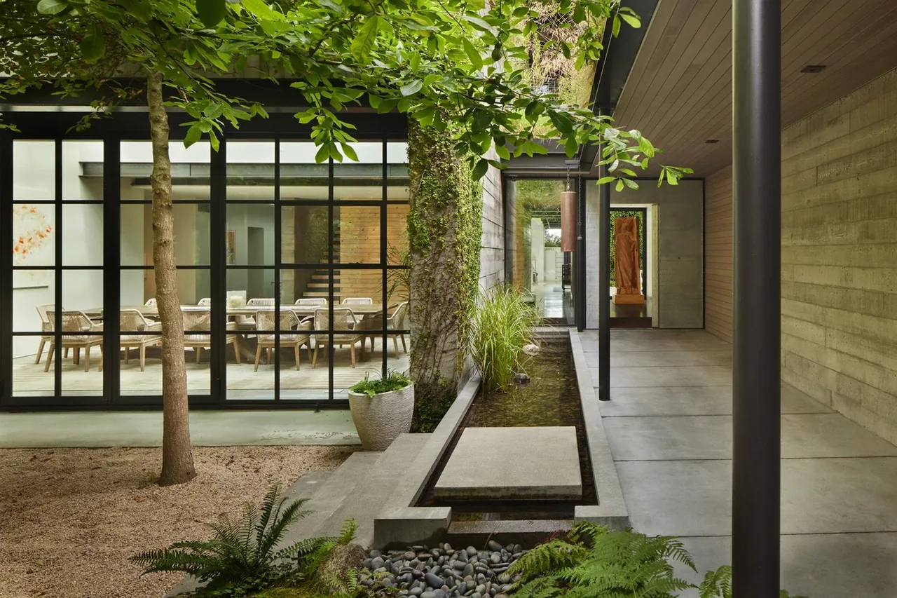 Courtyard water feature and outdoor seating area visible through large grid windows at The Bluff project.