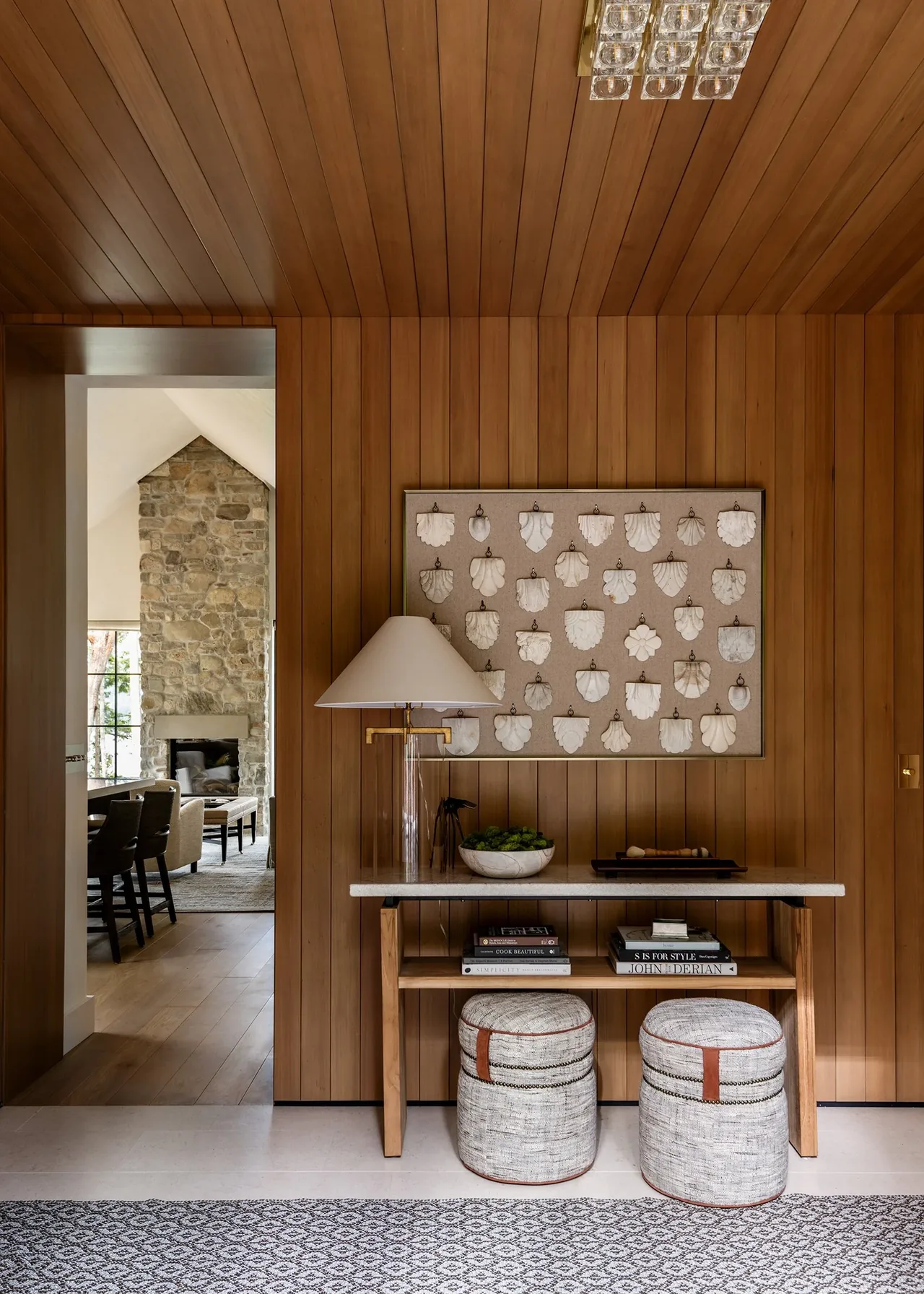Entryway with wood-paneled walls and console table leads to a living room featuring a stone fireplace at Keystone Cottage.