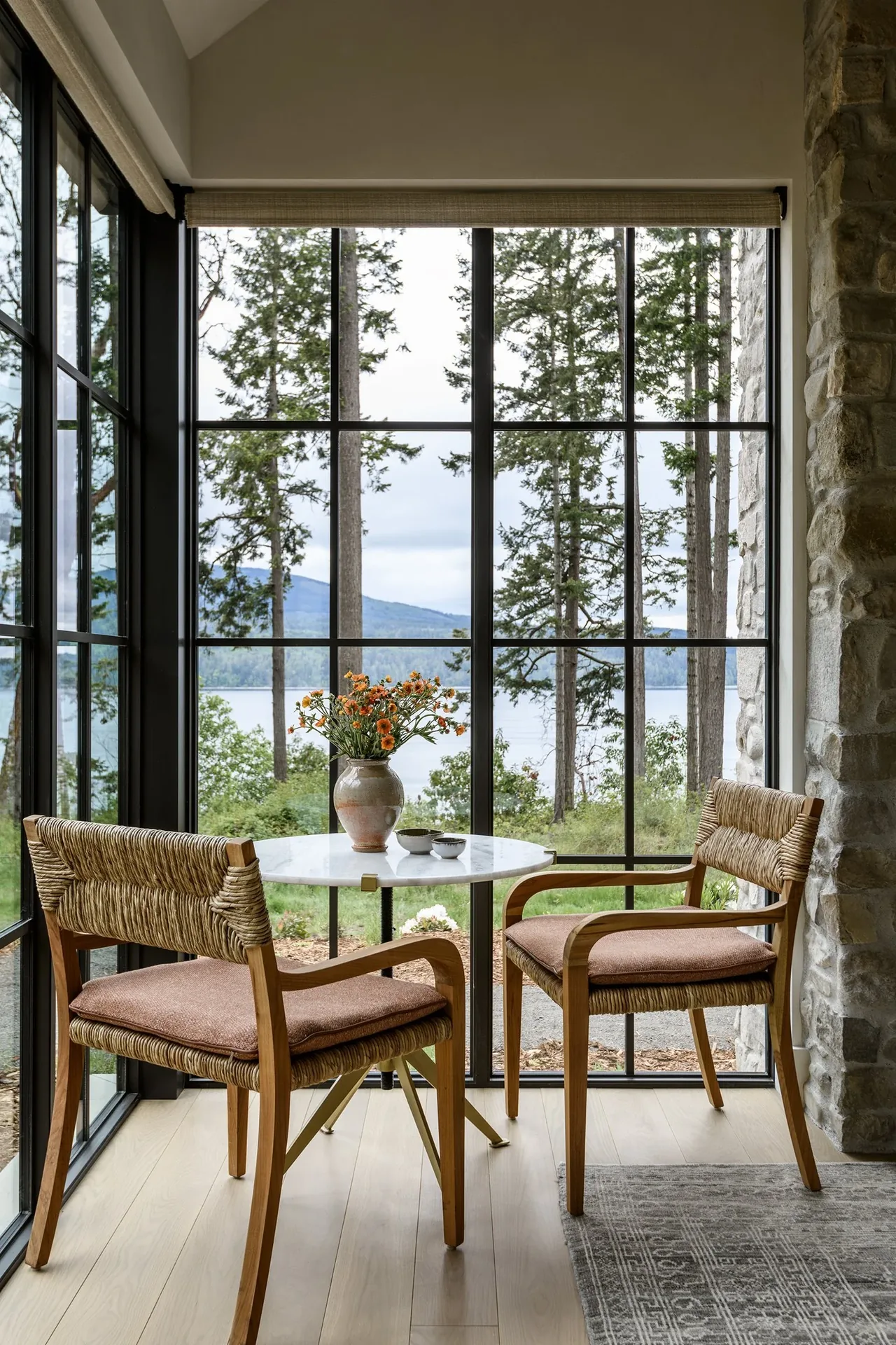 A small seating nook with woven chairs and a white round table framed by large black-framed windows at Keystone Cottage.