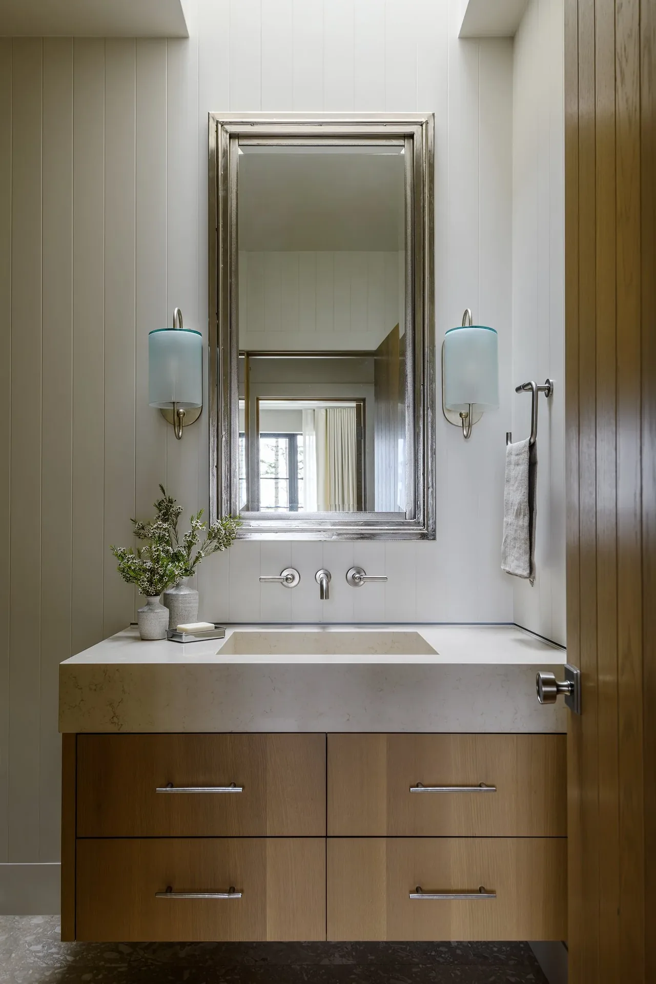 Bathroom vanity with marble countertop, silver framed mirror, and modern wall sconces at Keystone Cottage.