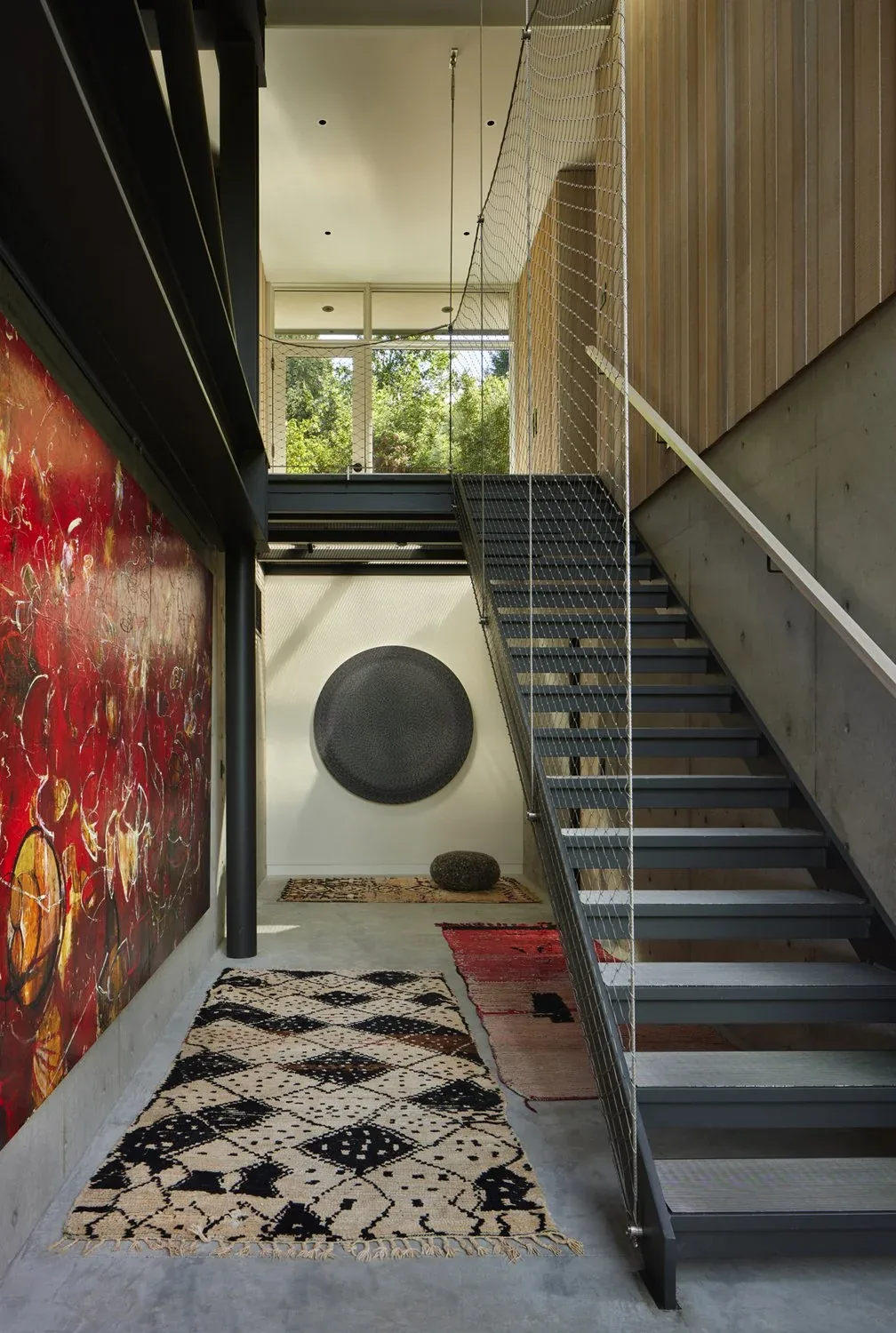 Stairway featuring metal steps with mesh railing, adjacent to a red abstract painting on the wall in Creek House.