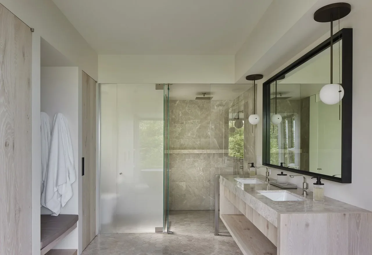 Bathroom in Creek House by DeForest Architects with a double vanity and frosted glass shower enclosure.