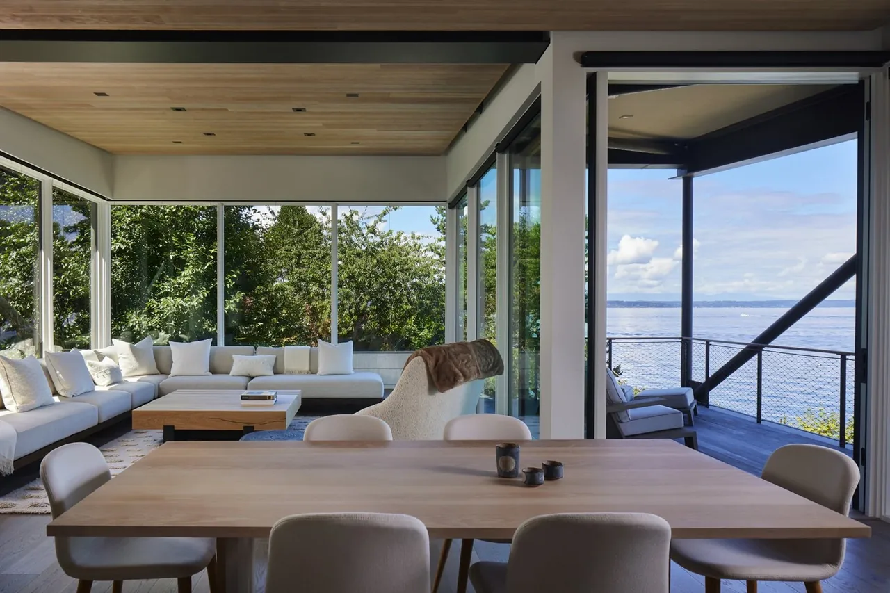 Open living and dining area with floor-to-ceiling glazing showing landscape and water views.