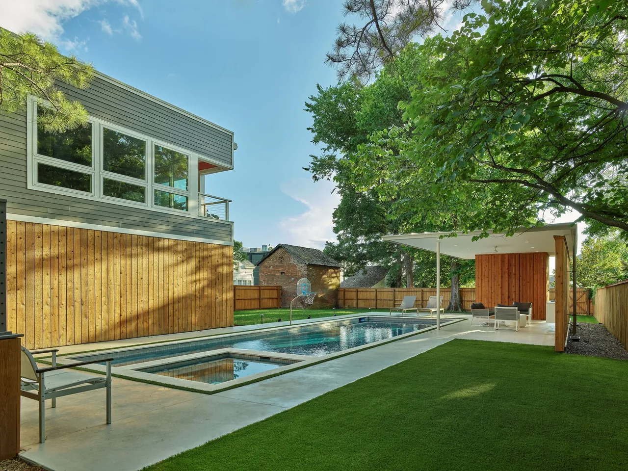 The Werner Pool & Pavilion features a modern flat-roofed pavilion and wood privacy walls around a swimming pool and lawn.