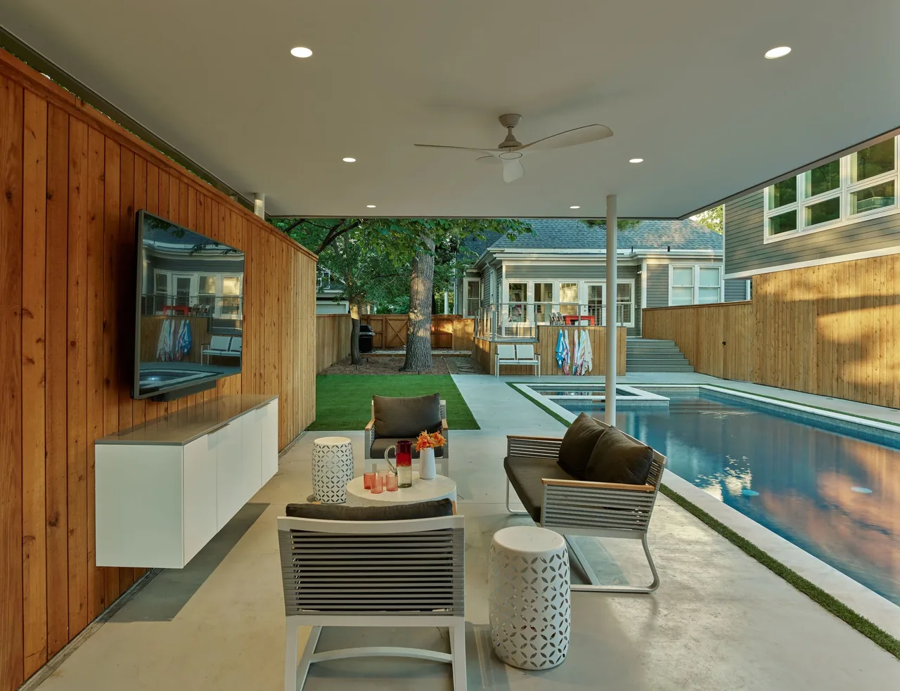 The pavilion features a covered seating area with wood privacy walls and an outdoor TV facing the pool.