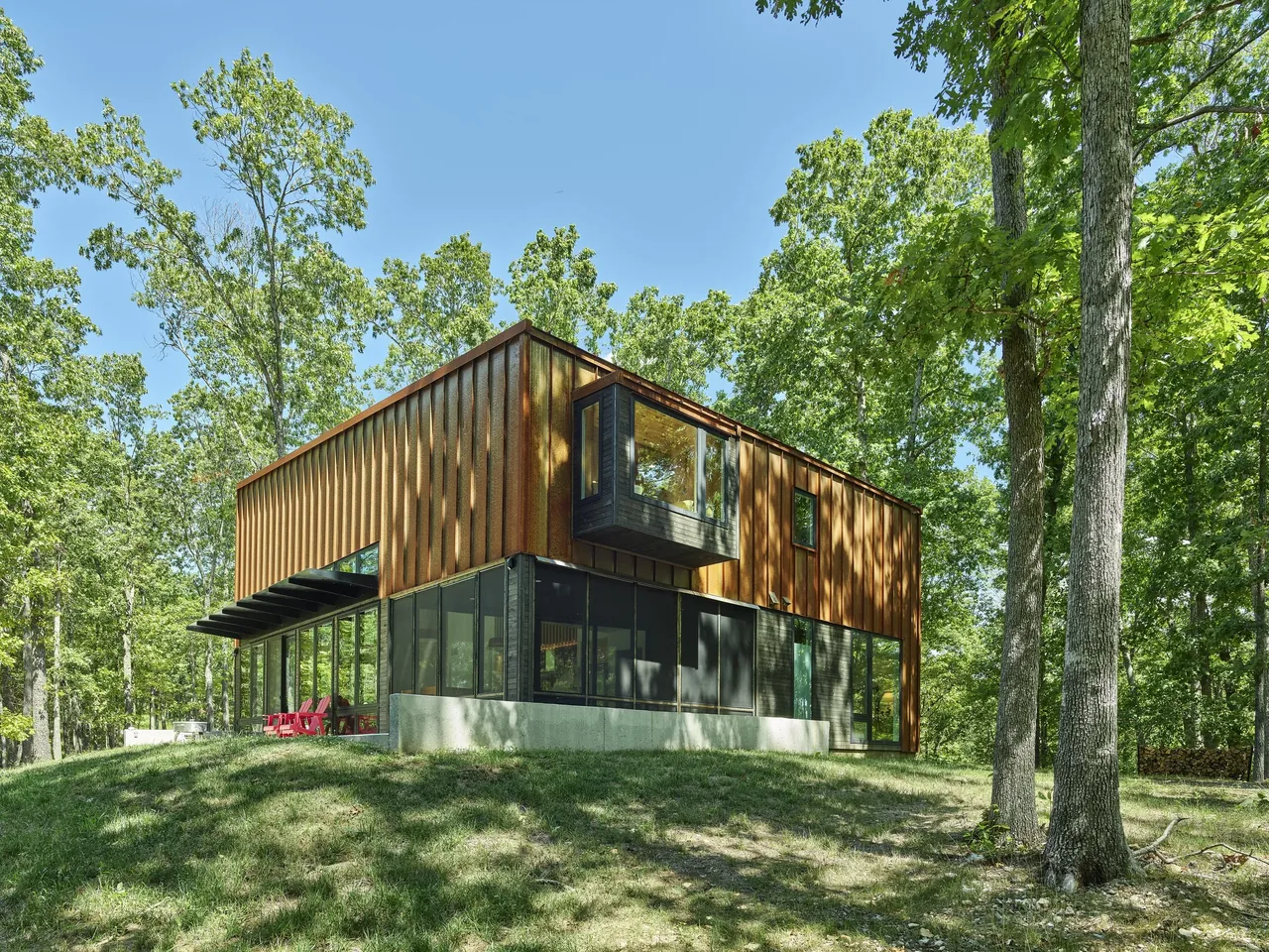 Eclipse Ridge features a rust metal facade with large black-framed windows and red patio chairs on the porch.