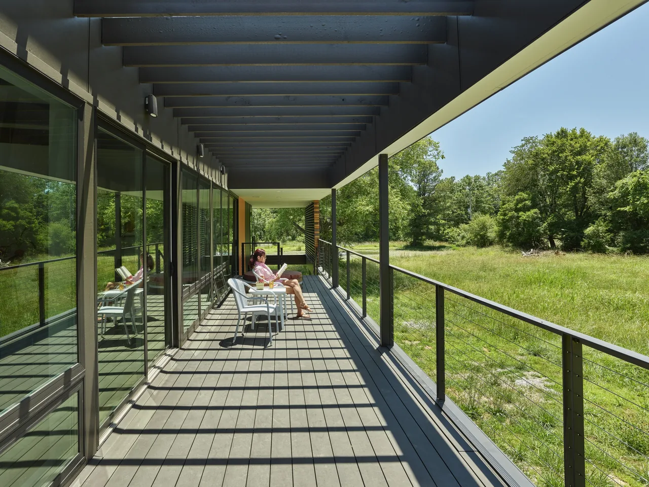 Covered balcony with wood decking and cable railing at the Willis Residence by deMx Architecture.