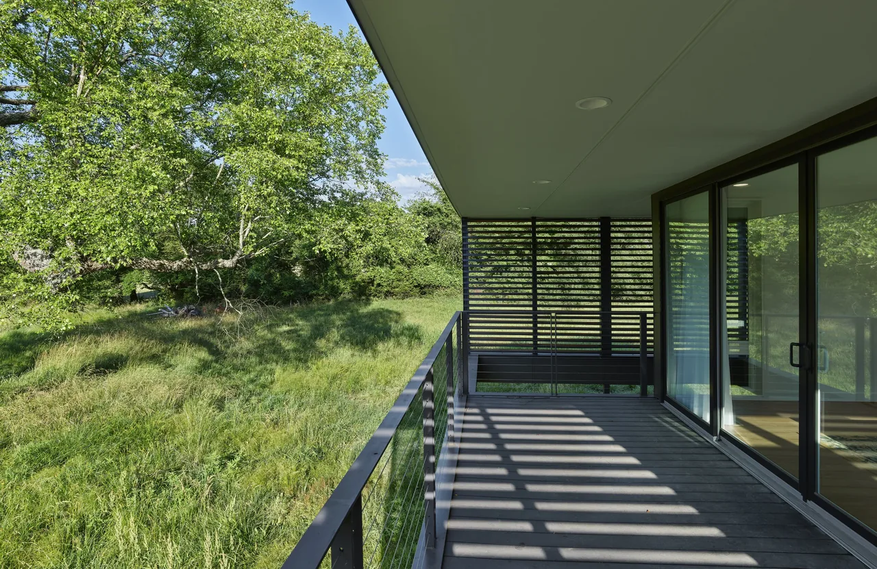 The Willis Residence features a wood deck with cable railing and a wood slat screening wall, connected to the interior by sliding glass doors.