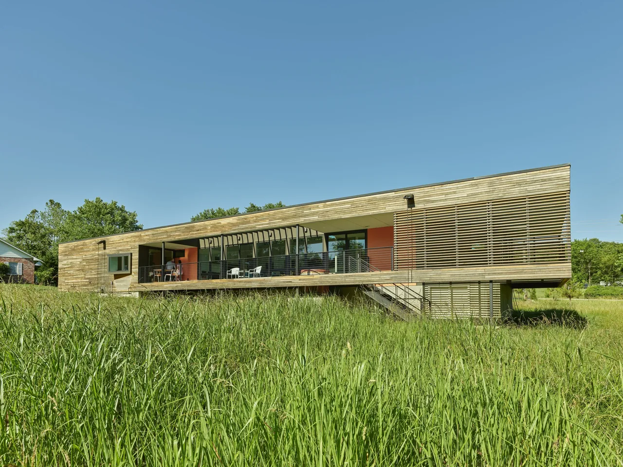Willis Residence by deMx Architecture features a raised wood structure with a covered deck and horizontal wood slat screening.