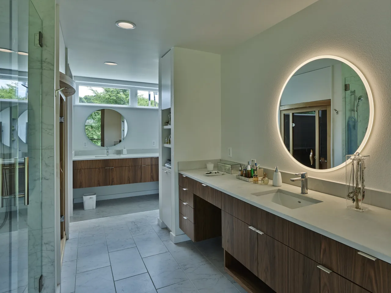Bathroom features include a backlit circular mirror, wood veneer vanity cabinets, and a marble tiled floor.