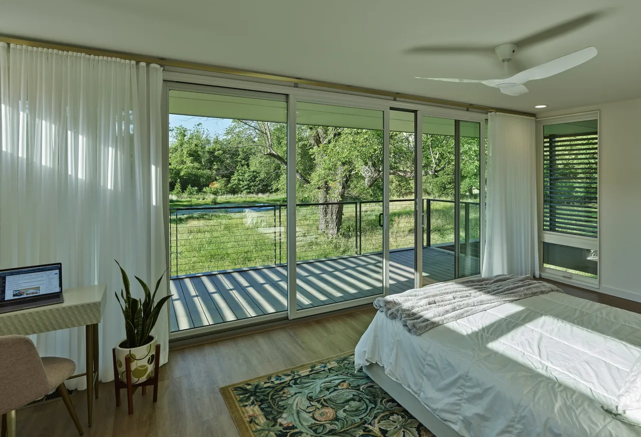Willis Residence bedroom features large sliding doors opening to a deck with cable railing and expansive nature views.