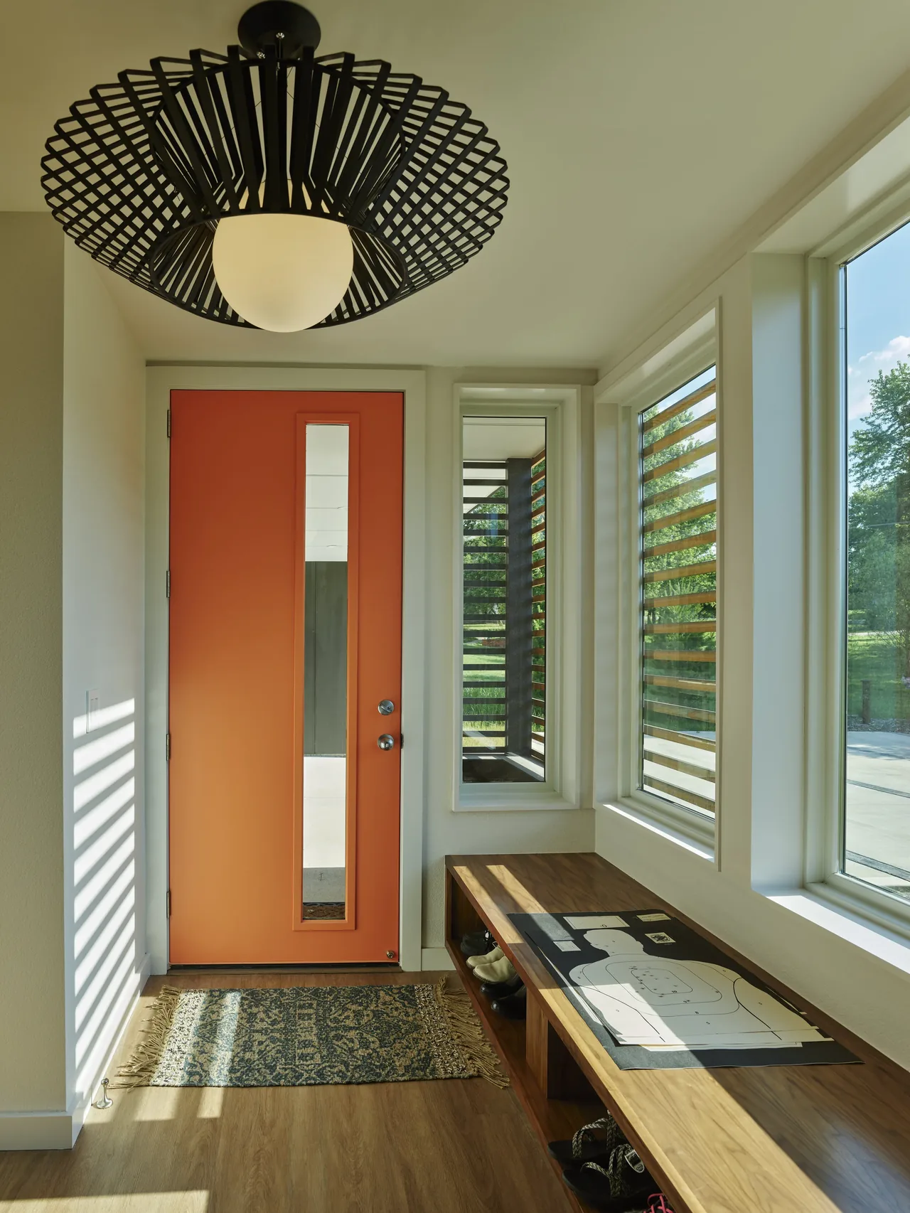 The Willis Residence entry features an orange front door with a vertical window and a distinctive black pendant light fixture.