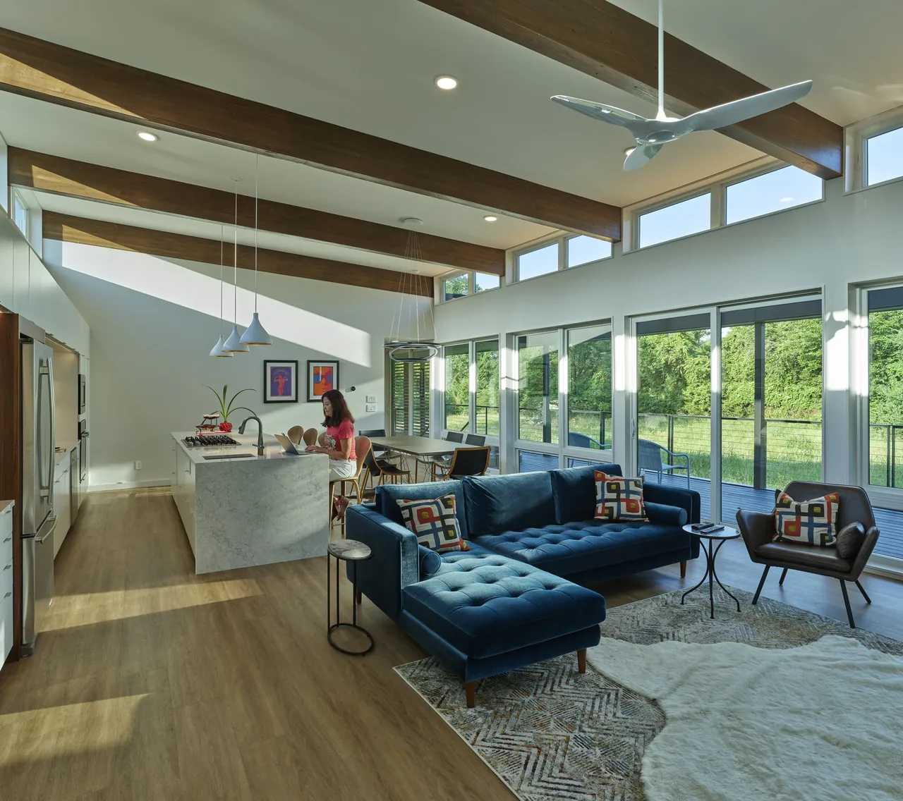 Open living and kitchen space featuring floor-to-ceiling glazing and exposed wood beams in the Willis Residence.