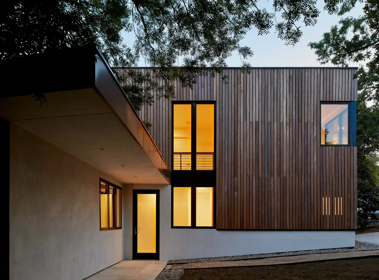 The Jesse Street House features vertical wood siding and black-framed windows with a flat roof design.