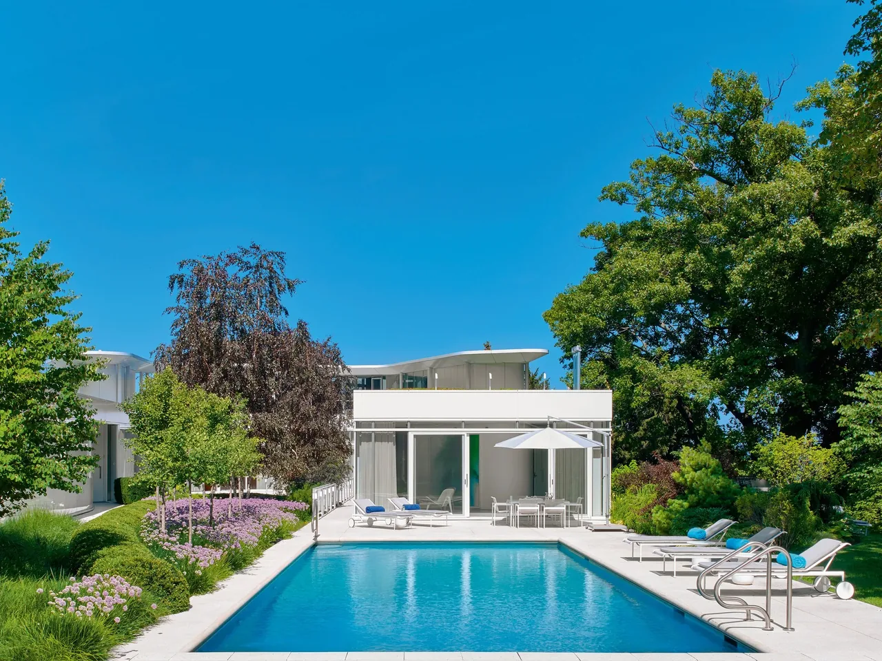 The Lake Michigan Residence features a U-shaped modern design with a swimming pool and landscaped garden by Dirk Denison Architects.