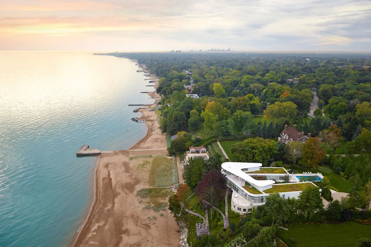 The Lake Michigan Residence features a curved butterfly roof and green roof near the shoreline, designed by Dirk Denison Architects.