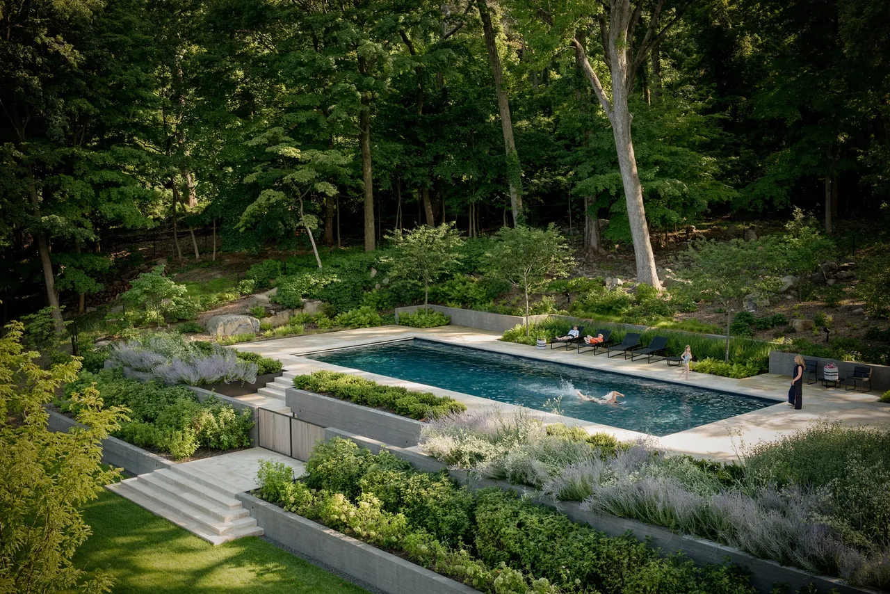 Outdoor swimming pool with concrete terrace and landscaped planting beds at Neiderhurst Estate.