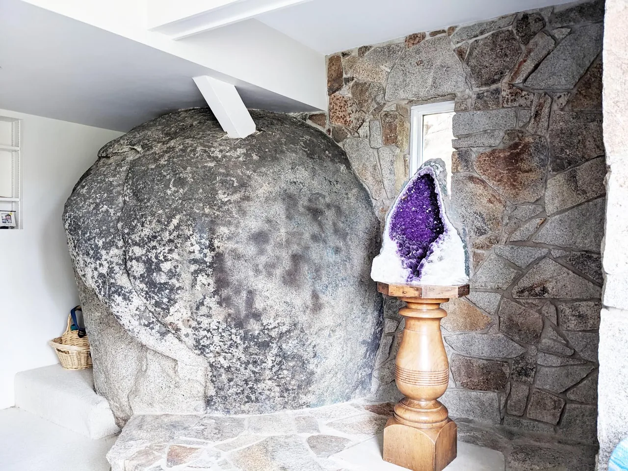 Room interior with a large embedded natural boulder and an amethyst geode on a tall wooden stand, part of the Bold Tahoe Lodge Transformation.