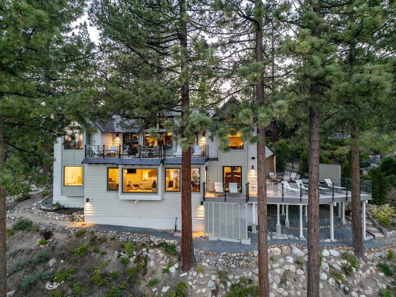 The Bold Tahoe Lodge Transformation features an elevated rear deck and large windows overlooking the forest setting.