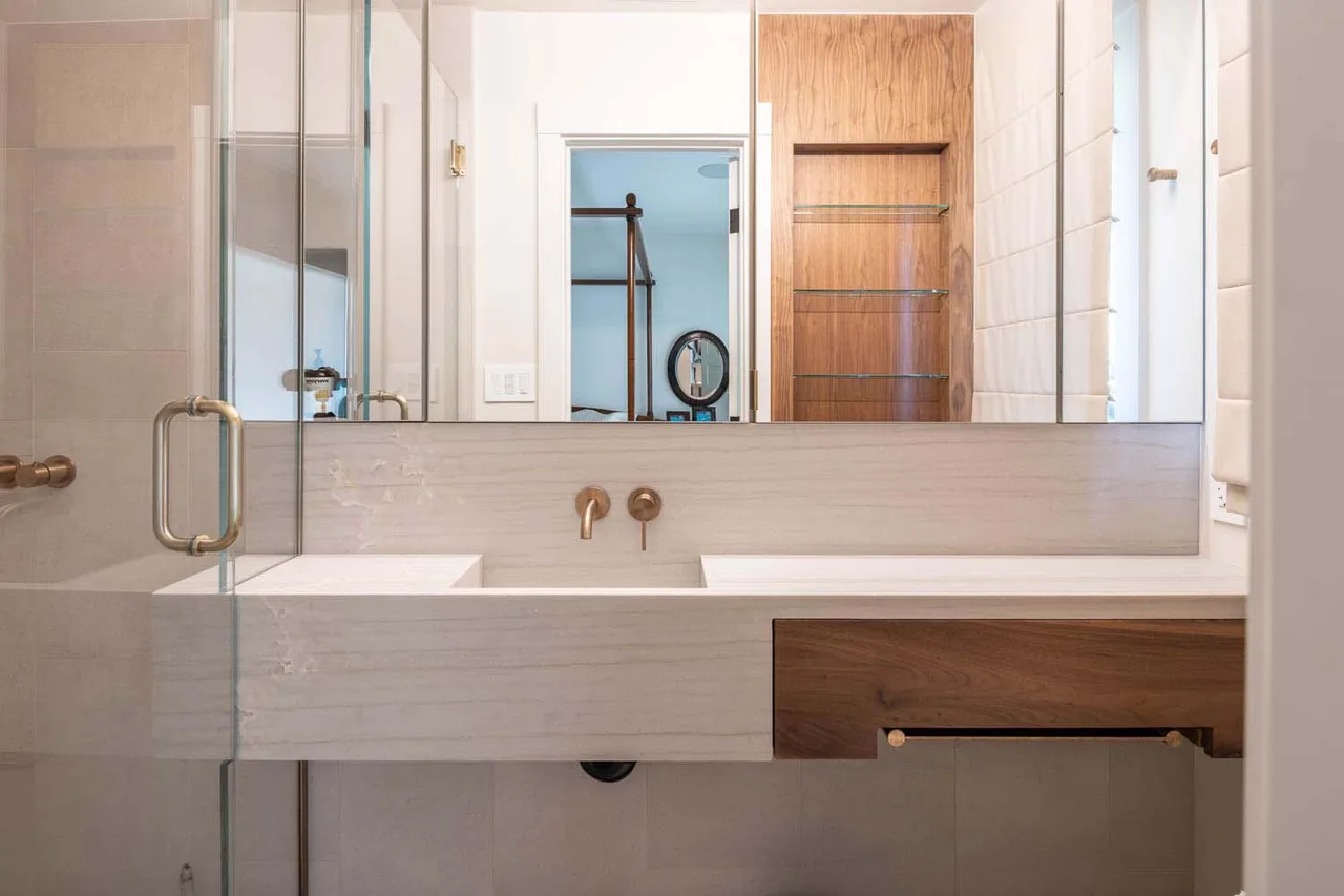 Bathroom featuring a double vanity with brass wall-mounted faucets and wood cabinetry in the Bold Tahoe Lodge Transformation project.
