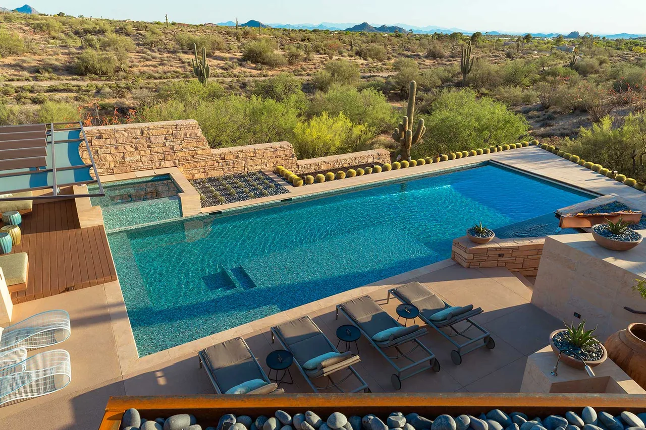 Saguaro Ridge pool area featuring stone cladding, desert landscaping, and mountain views at sunset.