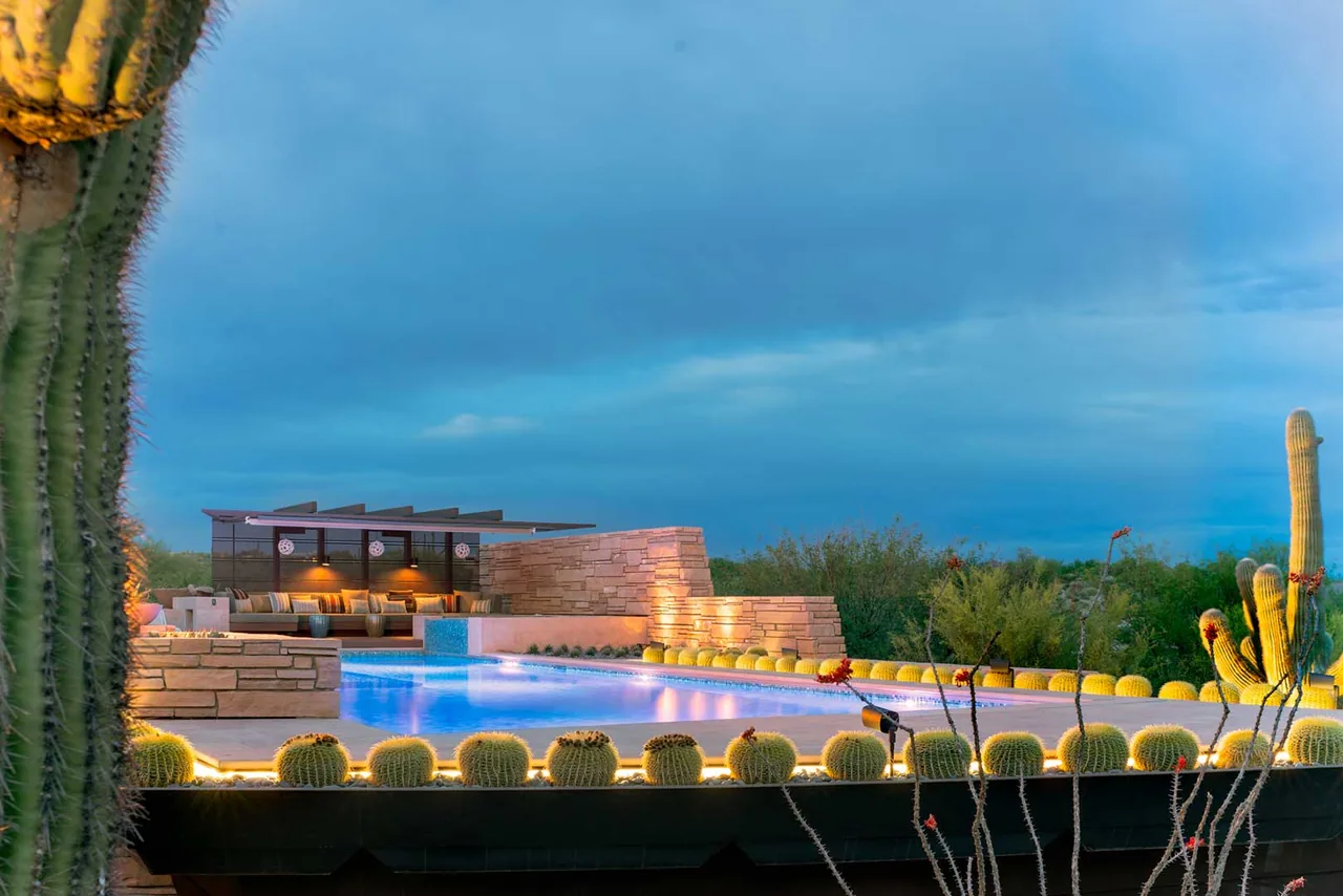 Saguaro Ridge pool area features a rectangular pool edged by cactus plants and stone cladding with lounge seating and mountain views.