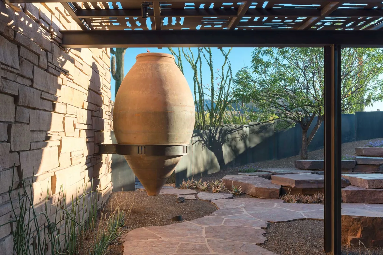Terracotta urn art piece hangs in a desert garden with stone pathways and native plants at Saguaro Ridge.