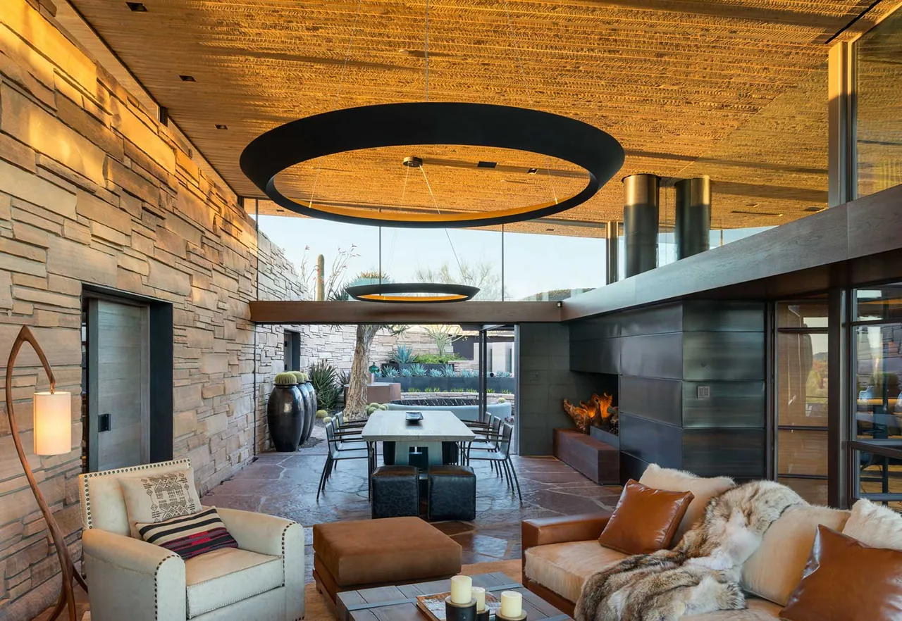 Interior view of a modern open living and dining space featuring a sloped wooden ceiling and stacked stone walls at Saguaro Ridge.