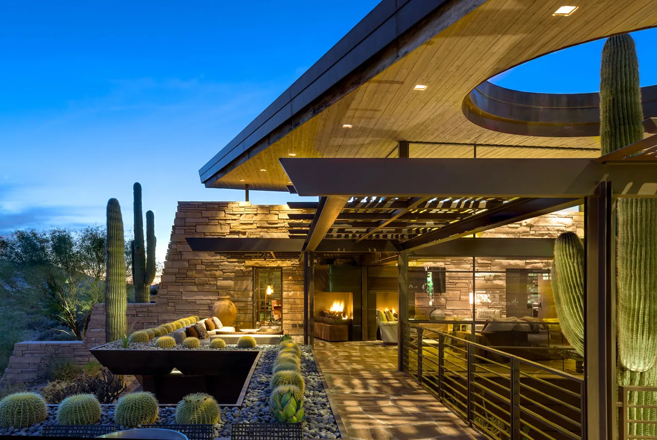 Saguaro Ridge outdoor living space features stone walls, metal pergola, and desert landscaping with cactus.
