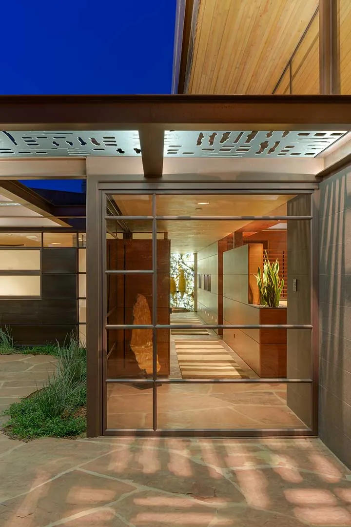 Entrance view highlighting metal-framed glass door, stone flooring, and wood ceiling of Saguaro Ridge project.