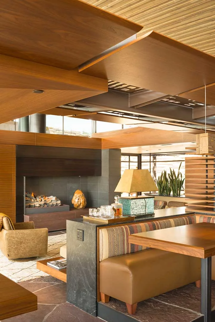 Living space features a built-in bench dining area, stone fireplace, and decorative wooden ceiling panels.