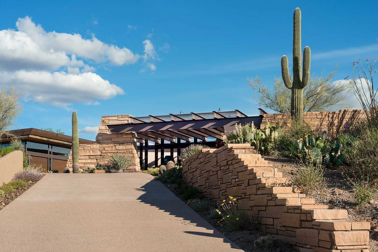 The Saguaro Ridge house by Douglas Fredrikson Architects features stone masonry with desert landscaping and a steel pergola.