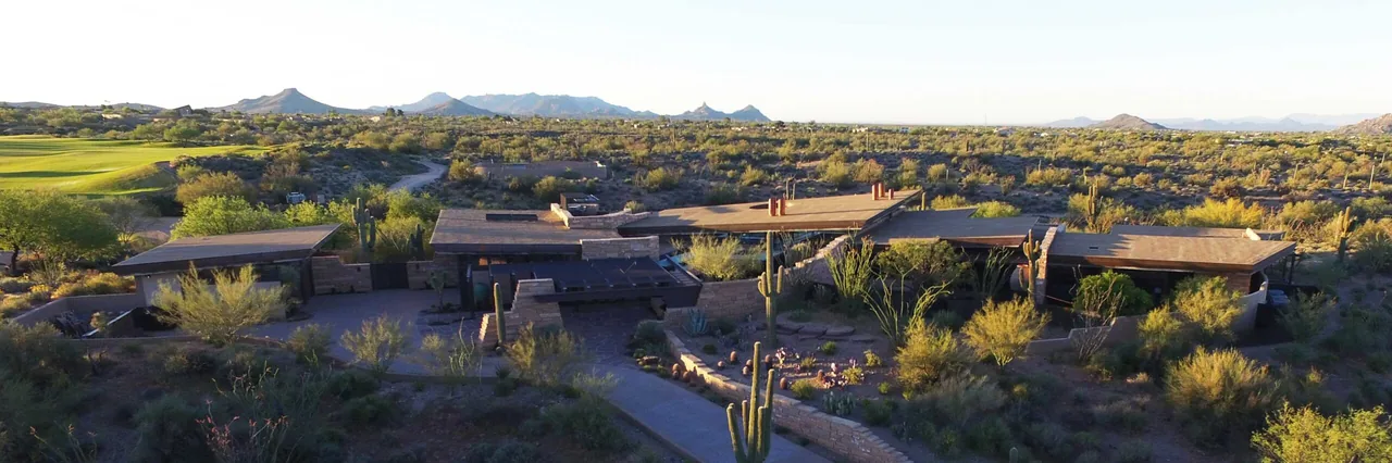 Saguaro Ridge features modern single-story architecture with flat roofs and desert landscaping set against a mountain backdrop.