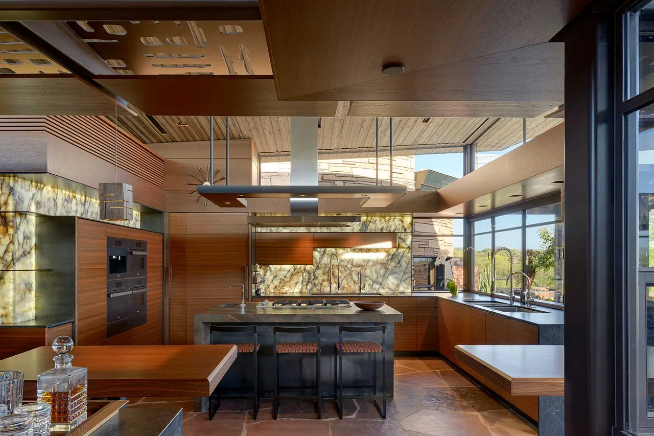 Kitchen in Saguaro Ridge featuring a backlit stone panel backsplash and wood ceiling panels by Douglas Fredrikson Architects.