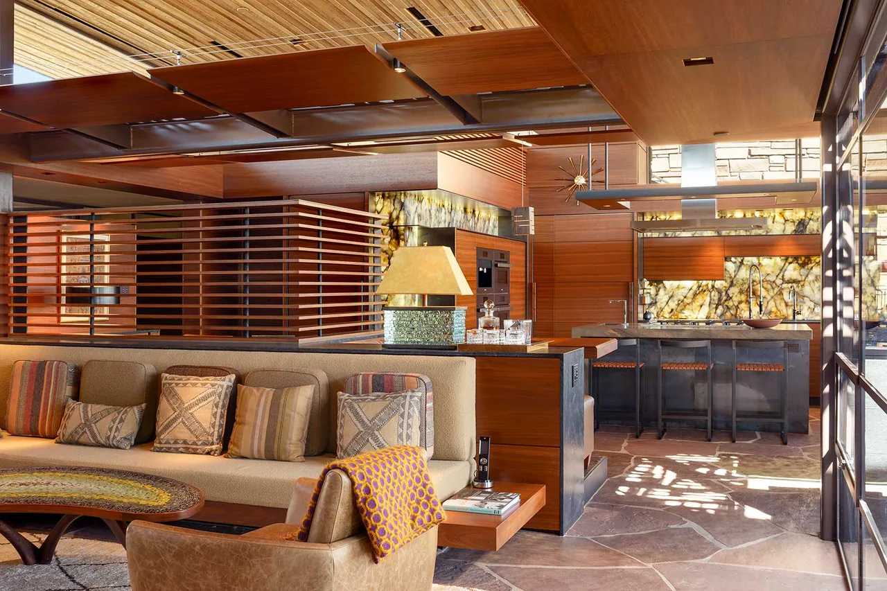 The Saguaro Ridge project by Douglas Fredrikson Architects features midcentury modern design with wood ceiling panels and a striking backlit stone panel in the kitchen.
