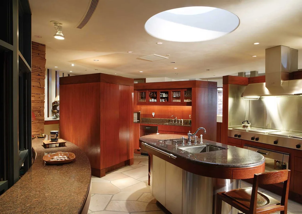 The kitchen at El Rojo Grande features a curved island with a sink, circular skylight, and stainless steel appliances.
