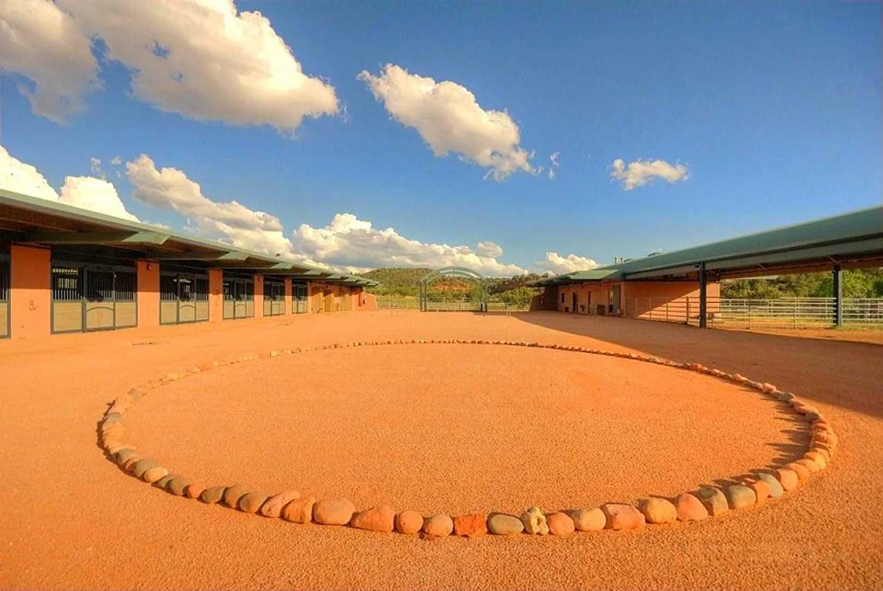 El Rojo Grande features courtyard-style open space flanked by buildings with arched metal roofs and desert landscaping.