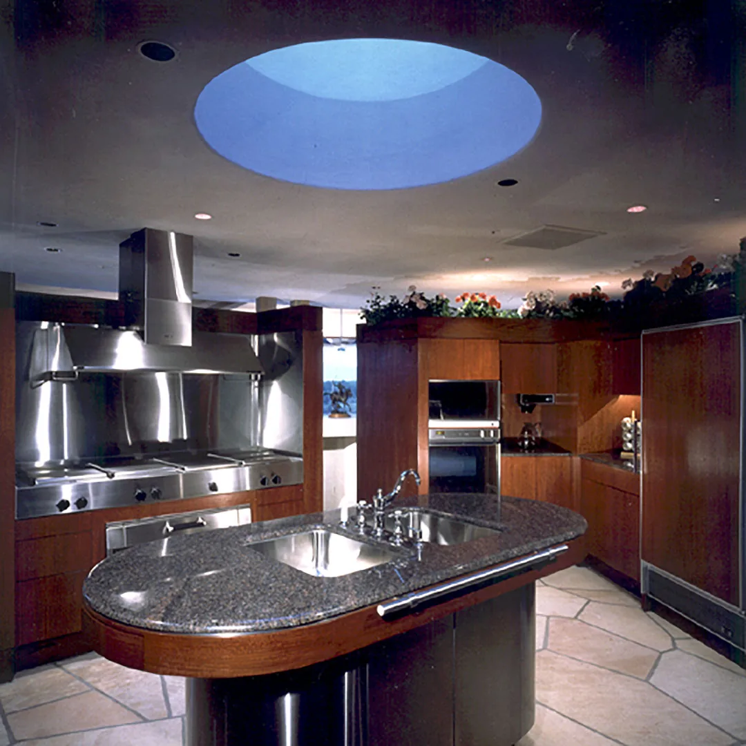 Kitchen features a curved granite island with double sink, stainless steel appliances, and a large circular skylight above.