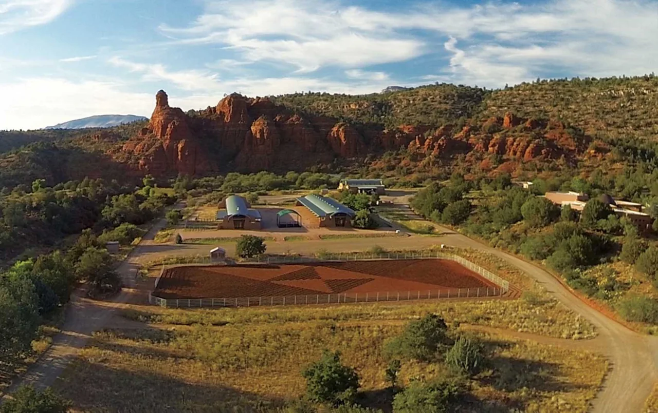 El Rojo Grande features buildings with arched metal roofs situated in a desert landscape with red rock formations.