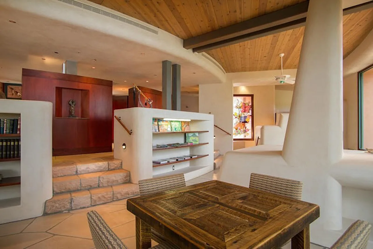 The El Rojo Grande project features curved plaster walls and a wood-paneled ceiling with stone steps leading to a raised living area.