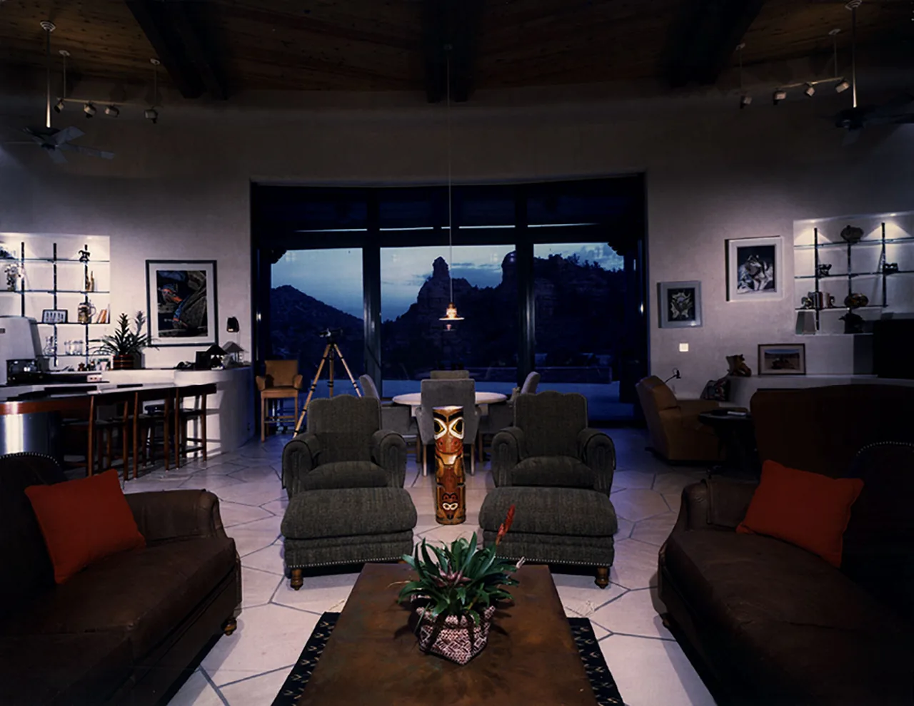 Living room with dark furniture and view of rugged mountains in the background at dusk.