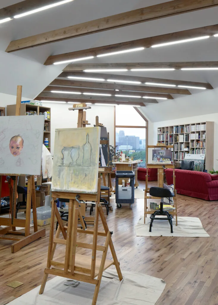 Artist studio with wood flooring, exposed wood beams on the ceiling, and large windows for natural light.