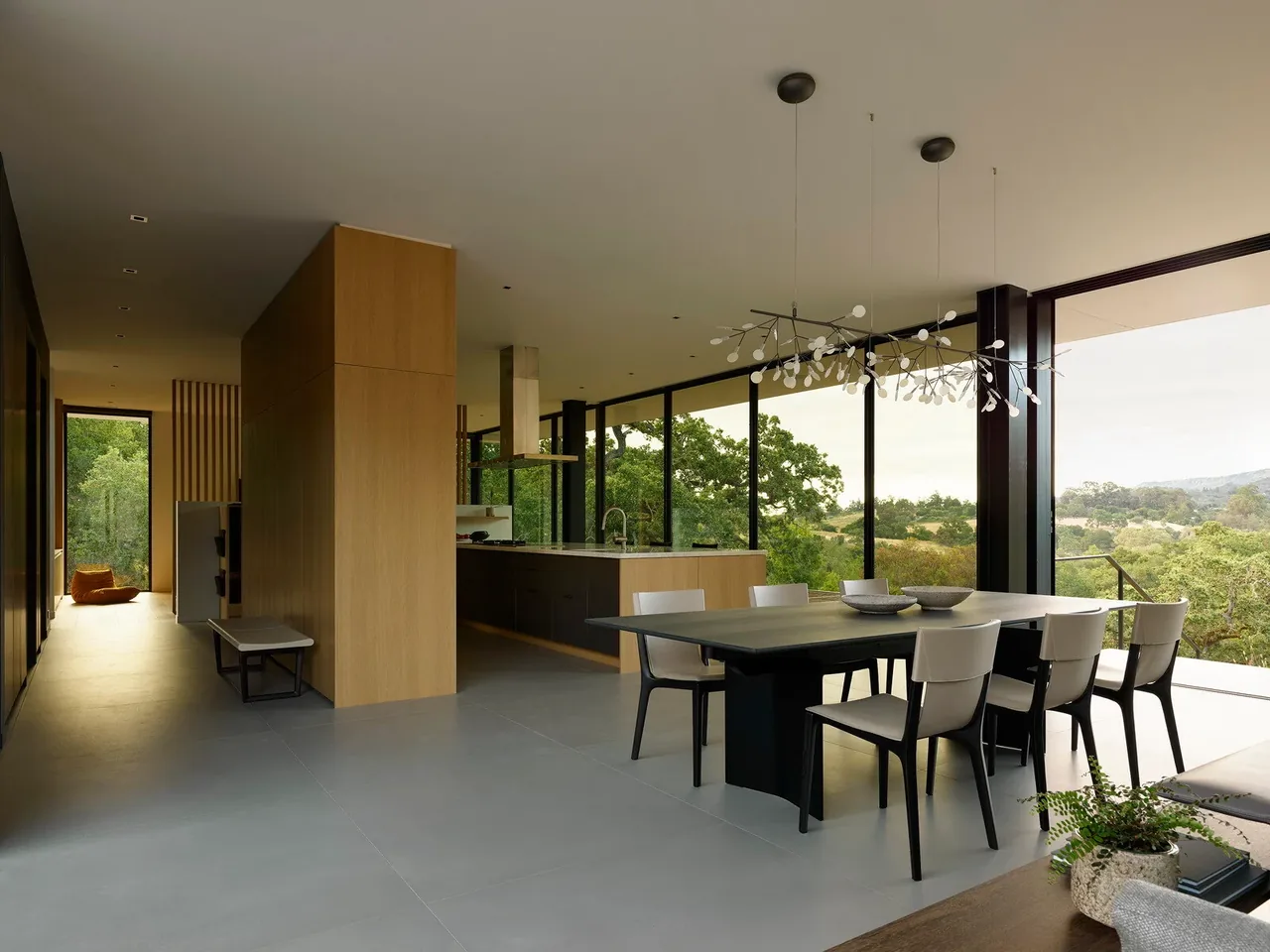 Open dining and kitchen space with floor-to-ceiling glazing offering views of surrounding greenery at the Westridge project.