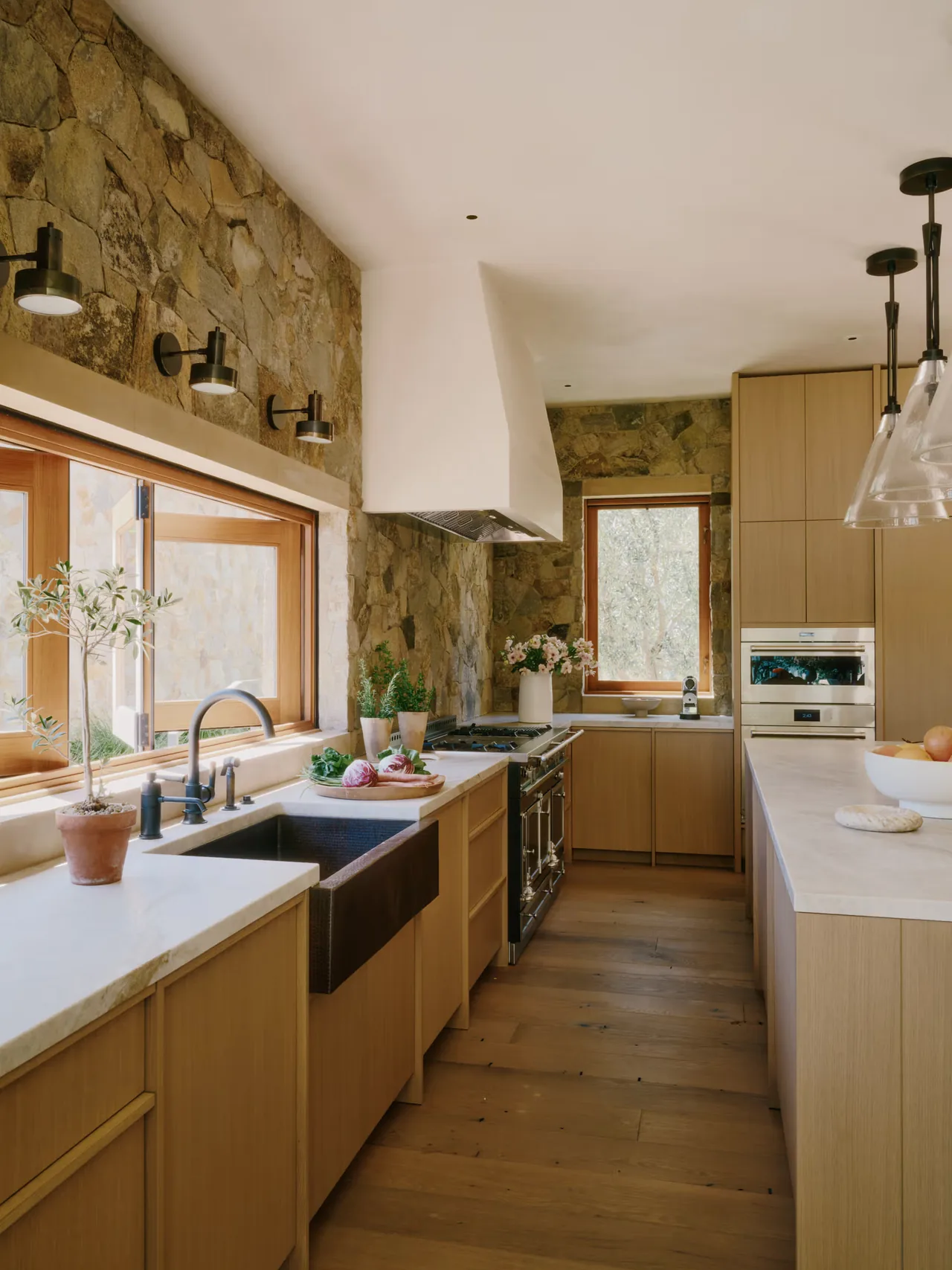 Kitchen interior of Stone Villa features natural stone walls, wood cabinetry, and stainless steel appliances.